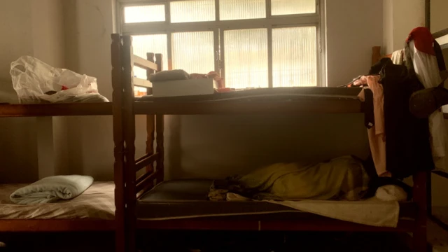 Quatro camas de beliche; uma delas tem pessoa dormindo