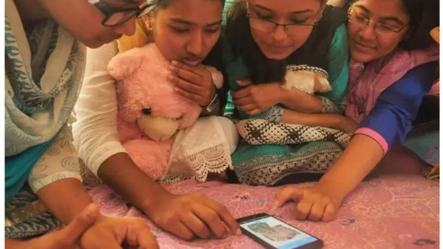 मोबाइल पर फेसबुक देखती लड़कियां