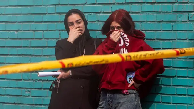 شهروندانی که صورتشان را گرفته‌اند تا از بوی سوختگی و اجسادی که زیر آور مانده‌اند دور بمانند. آنها شاهد کار گروه‌های امداد در تهران هستند. 