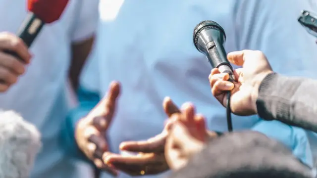 Diversos microfones direcionados a um entrevistado