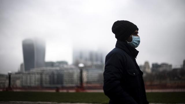 Un hombre camina por Londres con una máscara.