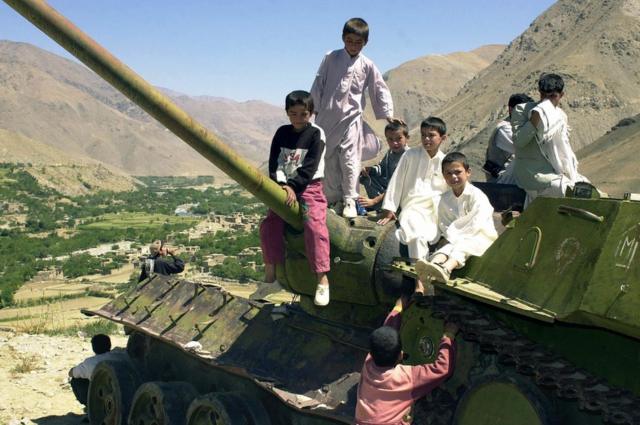 Afghan children play on the turret of an abandoned Soviet tank in the Panjshir valley , 2003