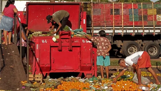 Pessoas buscando comida entre alimentos descartados, em foto de outubro de 2021