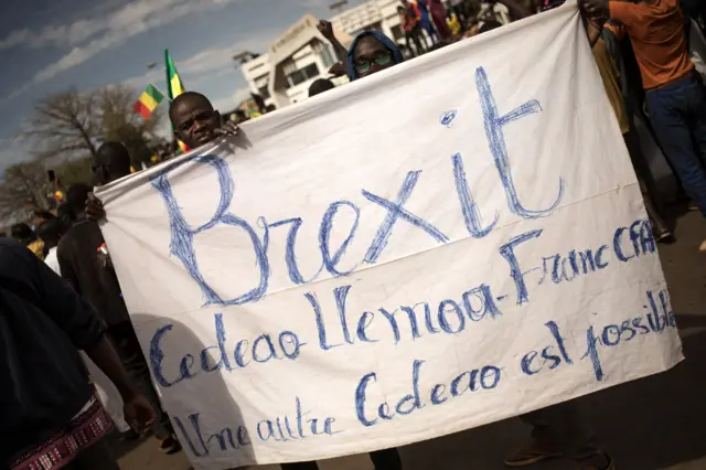 De jeunes manifestants tiennent une banderole appelant au « Brexit » de la Communauté économique des États de l'Afrique de l'Ouest lors d'une manifestation à Bamako le 14 janvier 2022.