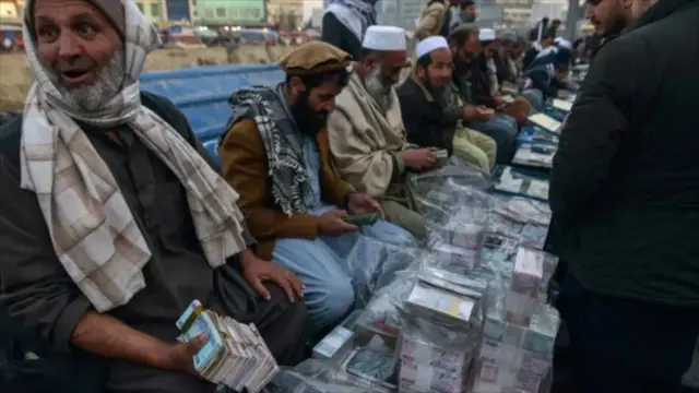 تصویر صرافان در کابل که بسته‌های زیادی از پول در میزهای پیش‌روی آنها دیده می‌شود