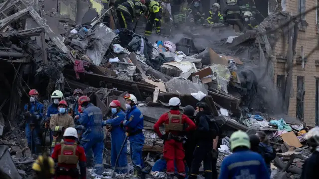 يواصل عمال الإنقاذ البحث عن أشخاص تحت أنقاض مبنى سكني دمره قصف صاروخي روسي في كييف