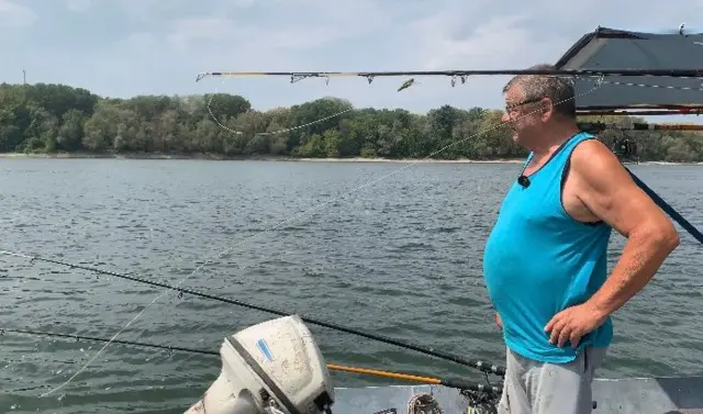 Čovek u plavoj majici na čamcu gleda u Dunav