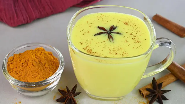 Un vaso de leche con cúrcuma dentro, lo que le confiere un color amarillo pálido.
