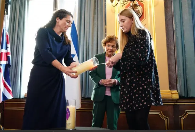 هیزل کامرون،‌ مسئول امور حقوق بشر وزارت خارجه بریتانیا و جانین وبر، یکی از بازماندگان هولوکاست در حال روشن کردن شمع در مراسم یادبودی که در محل وزارت خارجه در لندن برگزار شد