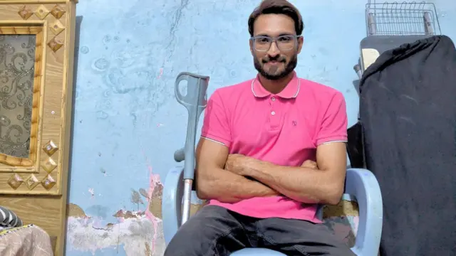 ချိုင်းထောက်ကိုညာဘက်ပေးမှာချထားပြီး ခုံမှာထိုင်နေတဲ့ အမီရာ အာလီ