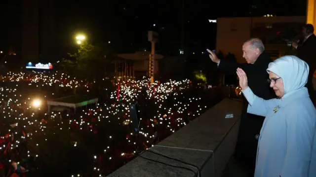 দলীয় সদর দফতরের ব্যালকনি থেকে সমর্থকদের দিকে হাত নাড়ছেন মি. এরদোয়ান এবং তার স্ত্রী