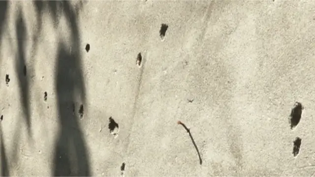 दफ़्तर की एक दीवार पर ग्रेनेड हमले से निकले छर्रे और धातु से बने कई गड्ढे बने हुए थे.