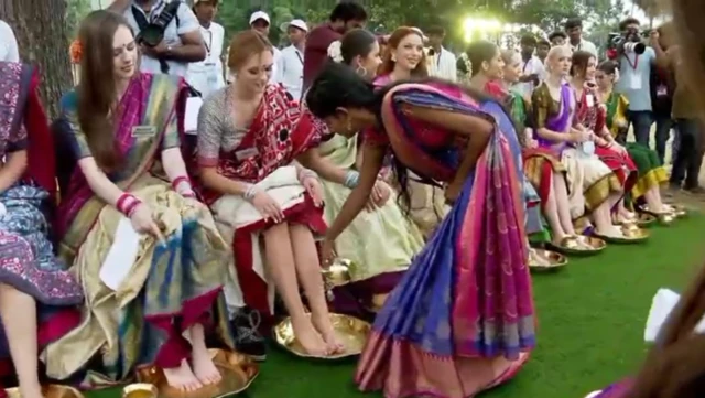 మిస్ వరల్డ్ పోటీదారు కాళ్లపై నీళ్లు పోస్తున్న మహిళ