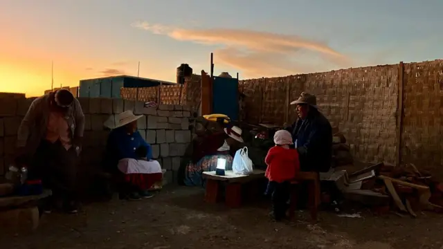 Varias personas se reunen alrededor de una linterna en el poblado de Pampa Clemesí en el sur de Perú. 