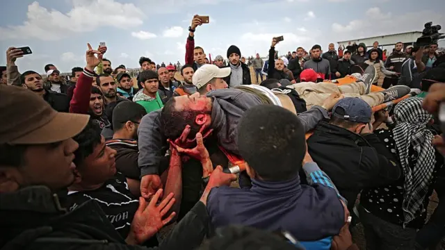 Palestinians carry the body of a youth who was shot dead by Israeli troops during clashes after protests along the border between Israel and Gaza Strip, 30 March 2018.