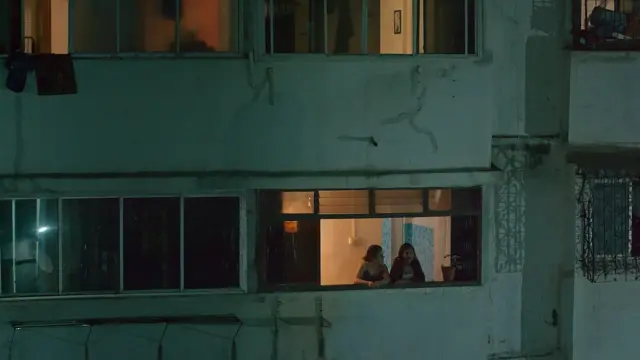 두 여성이 오래된 아파트 창문에서 이야기를 나누고 있다