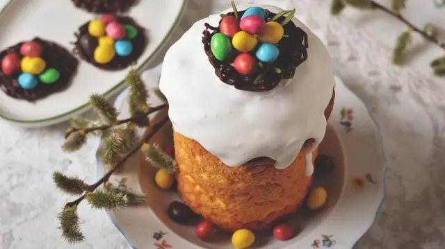 Паска, прикрашена білою глазур'ю і шоколадним гніздечком з кольоровими драже. 