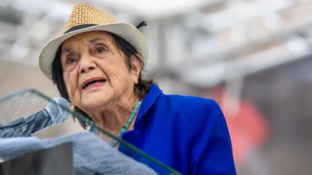 Primer plano de la cofundadora de la Unión de Trabajadores del Campo (United Farm Workers, UFW), Dolores Huerta, vestida con una chaqueta azul y con un sombrero, hablando en un atril con micrófono durante una protesta con el lema "Detengan la toma de poder de Trump" frente al Capitolio estatal de Texas el 16 de agosto de 2025 en Austin, Texas. (Foto de Brandon Bell/Getty Images)