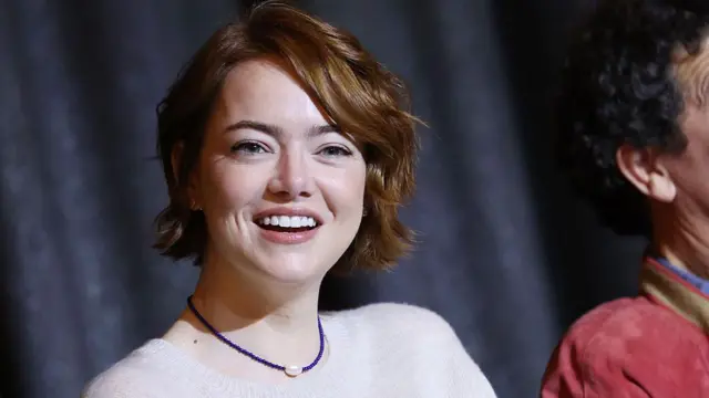 اما استون با پیراهن سفید و در حال لبخند