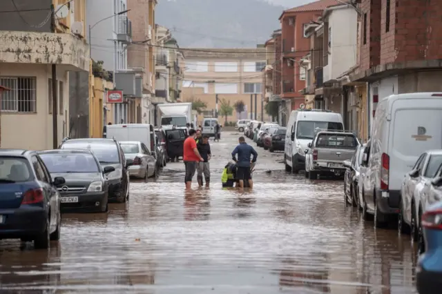 Homens à distânciajogo do foguetinho aviatormeio a rua alagadas