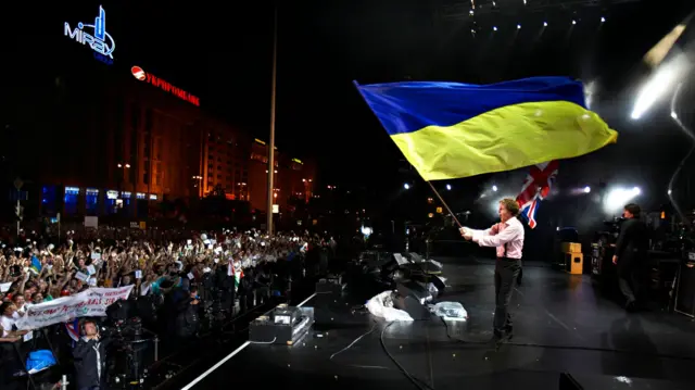 Ніч, Майдан Незалежності. Пол Маккартні на сцені розмахує синьо-жовтим прапором перед натовпом слухачів.