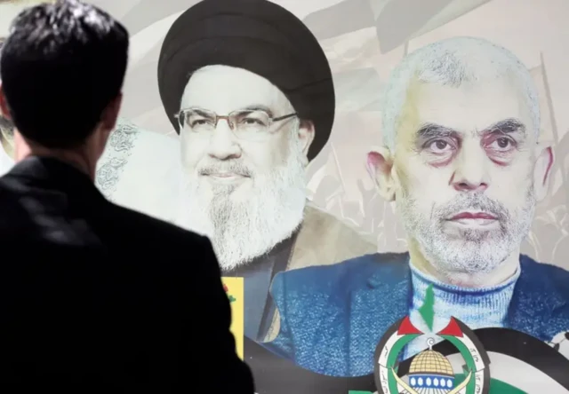 مردی به تصاویر دیواری سنوا و نصرالله نگاه می‌کند