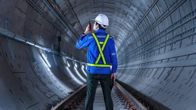 Foto ilustrasi. Seorang pekerja berada di terowongan dan mengenakan helm pengaman berwarna putih di lokasi konstruksi. 