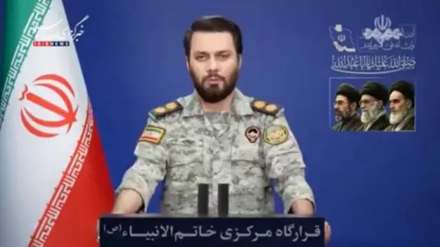 Khatam al-Anbiya falando em palanque, com bandeira do Irã ao fundo, à esquerda