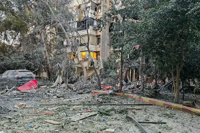 Zarar görmüş bir bina, bahçede kalıntılar