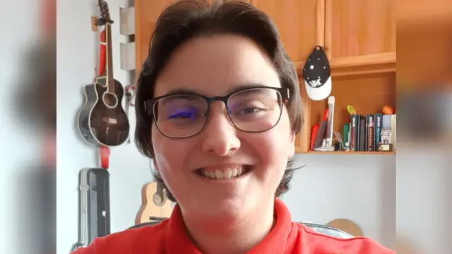 แดเนียล ยิ้มให้กับกล้อง สวมแว่นตา และเสื้อสีแดง