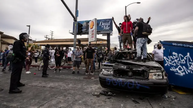 Manifestantes no topocupom desconto estrela betum carro da polícia queimadocupom desconto estrela betLos Angeles, Califórnia