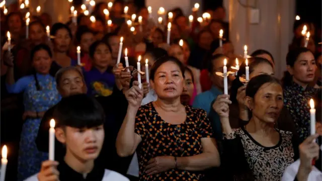 Mulheres rezam com velas