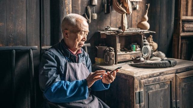 中国老人在木屋前用手机