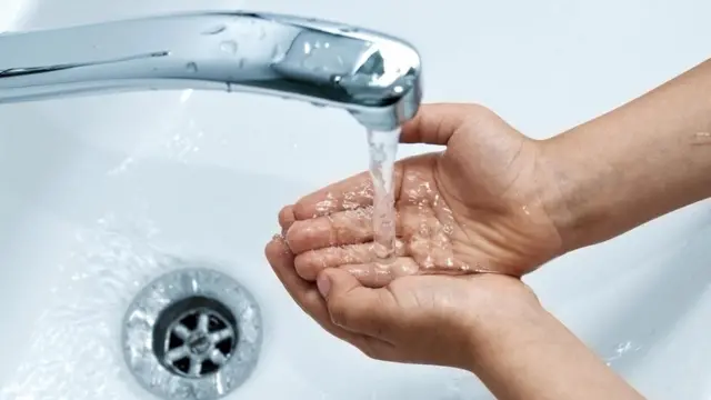 شخص يضع يده تحت ماء الصنبور