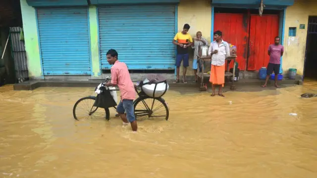 Seorang pria menenteng sepeda di jalanan yang kebanjiran di Dhobinala, India setelah hujan monsun, 07 Oktober 2019.
