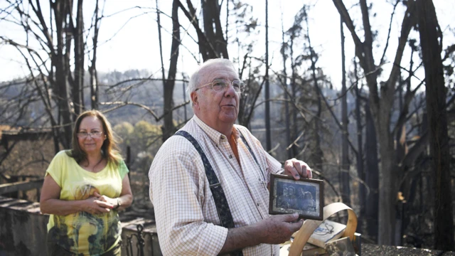 Un hombre y una mujere regresan a lo que queda de su hogar tras el incendio en Portugal en junio de 2017