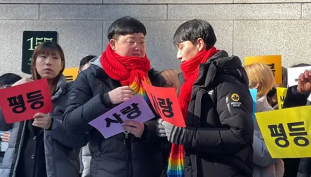 '사랑'이라고 적힌 종이를 들고 있는 소성욱 씨와 김용민 씨