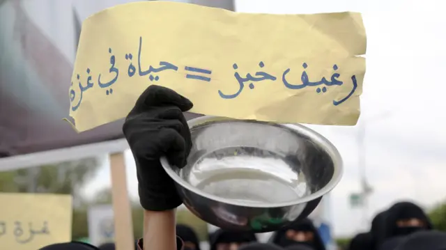 صورة لافتة ورقية صفراء كتب عليها "رغيف خبز يساوي حياة في غزة" رفعها طلاب وموظفون من جامعة صنعاء شاركوا في الاحتجاج الذي أقيم ضد استمرار القصف الإسرائيلي على قطاع غزة وحصار المساعدات إلى القطاع في 20 أغسطس 2025 في صنعاء، اليمن.