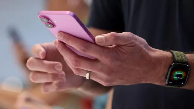 Un hombre con su Iphone en la mano. 