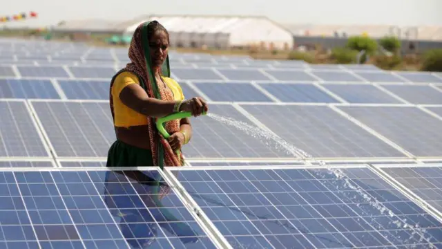 सौर पैनल को पानी से साफ़ करती एक महिला