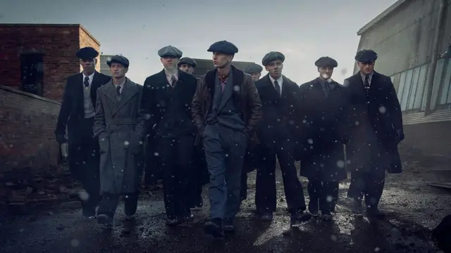 Кадр із фільму "Гострі картузи" - група чоловіків у пальтах і картузах йде вулицею