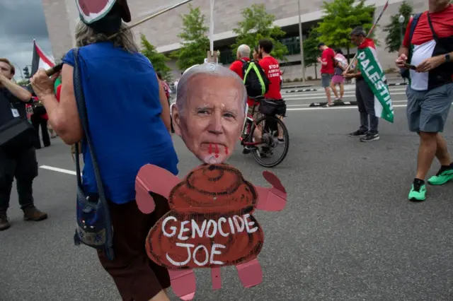 Manifestante segura bonecobet7k confiavelpapelão com rostobet7k confiavelBiden e dizeres 'Genocide Joe' (algo como Joe Genocida)