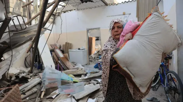 Seorang perempuan Palestina menyelamatkan barang-barang dari dalam rumahnya yang hancur akibat gempuran Israel di bagian selatan Jalur Gaza, 8 Oktober 2023 lalu.