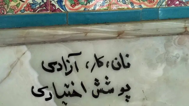 Grafiti bertuliskan "Roti, kerja, kemerdekaan, menutup tubuh sukarela"