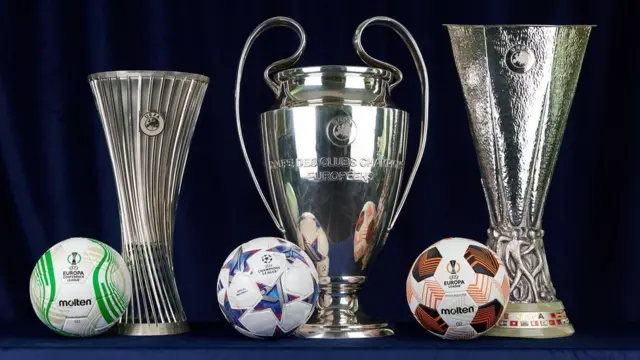 A photograph of the Europa Conference League, Champions League and Europa League trophies