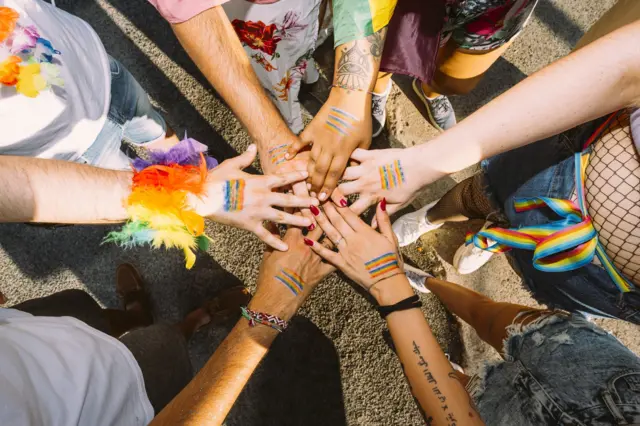 أشخاص يضمون أياديهم إشارة إلى وحدة "مجتمع الميم"