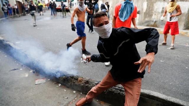 Một người biểu tình ném bình xịt hơi cay khi xô xát với Lực lượng Vệ binh Quốc gia trong một cuộc biểu tình gần Thủ đô Caracas.
