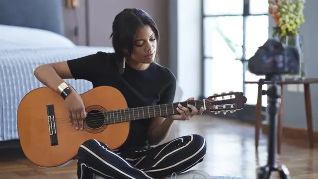 Una mujer sentada en el suelo tocando un instrumento
