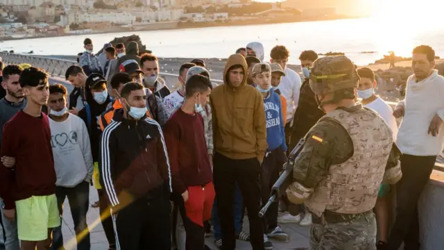 Oficial del ejército español habla con jóvenes migrantes.