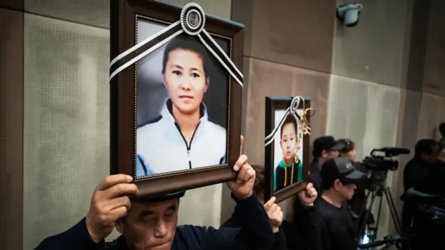 탈북민 한성옥 모자 사인규명 및 재발방지 비상대책위원회 관계자들이 2019 북한이탈주민 정착경험사례 발표대회장에서 한성옥 모자의 영정과 남북하나재단을 규탄하는 손팻말을 들고 있다